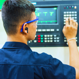 Male manufacturer wearing wireless headphones while working on machine